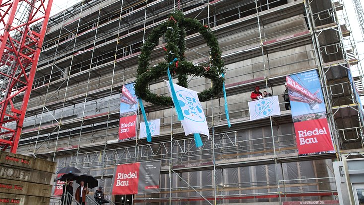 Topping-out crown in front of the DESYUM: As the foreman recites a poem he wrote himself to mark the completion of the shell of the DESY Visitor Centre DESYUM, the topping-out crown is hoisted in the view of Hamburg's Science Senator Katharina Fegeba