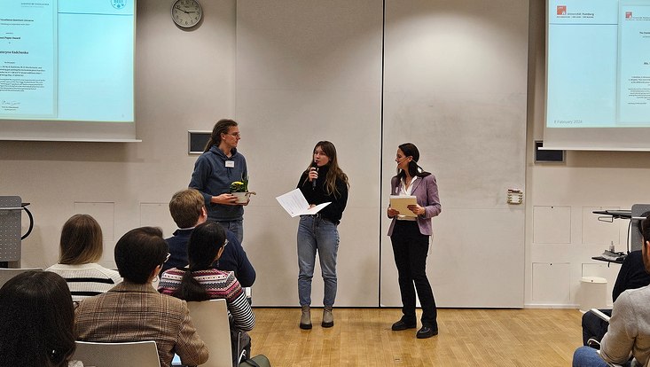 A photograph of one of the PhD best paper awards being presented to Kateryna Radchenko.