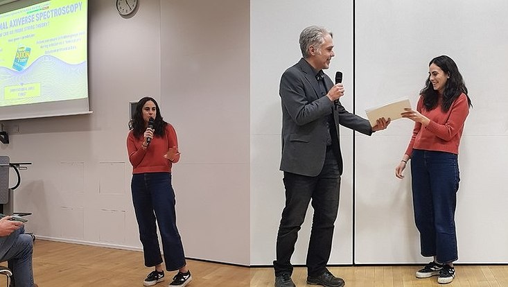 A photograph of the Best poster pitch and best poster prize being presented to Margherita Putti by QURS Director Dieter Horns.